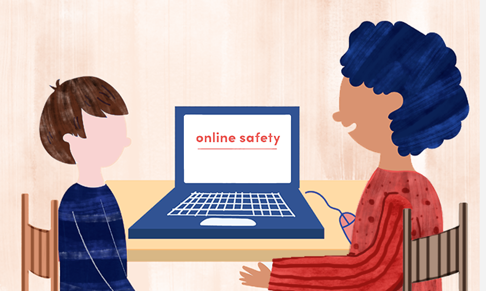 An older student explaining online safety to a younger child while a laptop is between them.