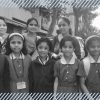 Female students of an Indian government school and their mothers smiling and staring at the camera.