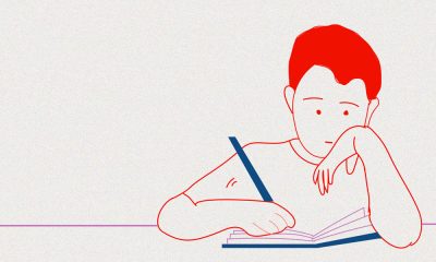 A teenage student sitting and writing in a notebook.