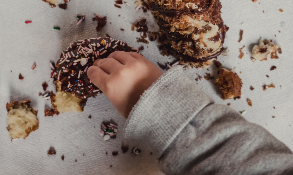 A child's hand smashes donuts