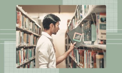 A young man picking up a Java book from a library